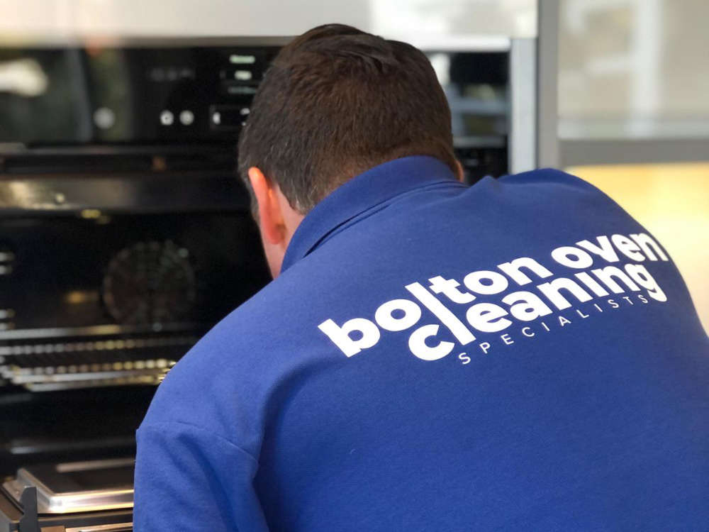Neil Cain cleaning an oven wearing Bolton Oven Cleaning Specialists branded tee shirt